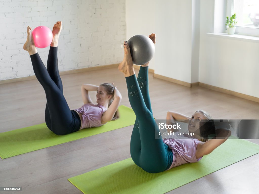 Premium Photo  Two flexible plastic girls doing pilates exercises on a mat  in a yoga studio sitting on a twine