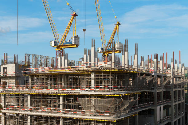 The construction of a multi-storey building. Two construction cranes on a building construction. Scaffolding on several floors. The construction of a multi-storey building. Two construction cranes on a building construction. Scaffolding on several floors. hoisting photos stock pictures, royalty-free photos & images