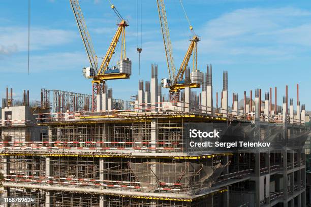 The Construction Of A Multistorey Building Two Construction Cranes On A Building Construction Scaffolding On Several Floors Stock Photo - Download Image Now