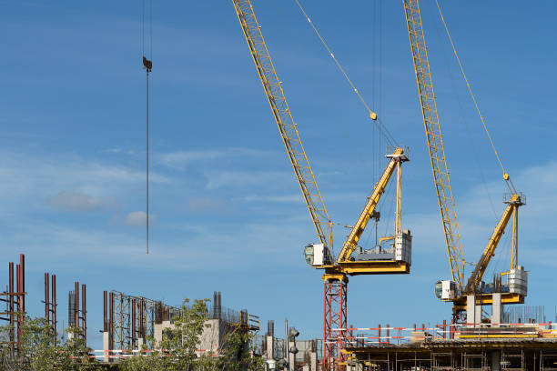 istock Two construction cranes at a construction site. Tall crane on a blue sky. The construction of a multi-storey building. 1168789665