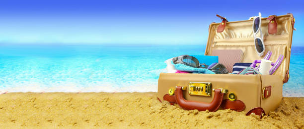 Full open suitcase on tropical beach background, banner