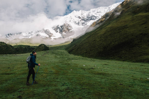 istock Side view of professional traveller with backpack travelling using trackking sticks enjoying wanderlust in Salkantay Peru.Young man tourist hiking on green landscape of hight mountains 1168790734