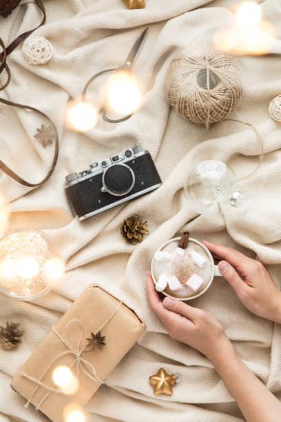Winter cozy background with cup of coffee and marshmallow, warm blanket and gifts. Flat lay