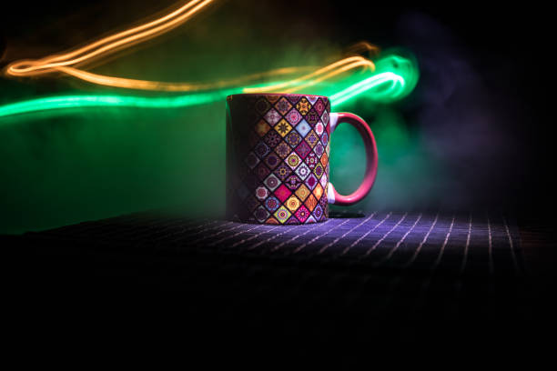 Beautiful eastern style textured ceramic cup of coffee (or tea) with smoke over dark toned background.