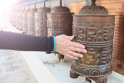 Person's hand rotates the prayer wheel with a written buddhist mantra \