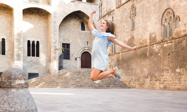 istock Girl jumping up against stone building 1168808624