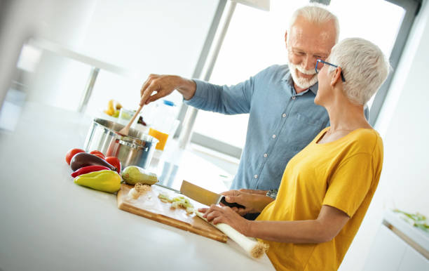 mature couple cooking lunch together. - cooking senior adult healthy lifestyle couple imagens e fotografias de stock