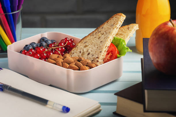 uno spuntino sano con te. bacche, noci e un panino in una scatola per il pranzo. prendersi cura della salute del bambino. colazione scolastica con mirtilli, mandorle e ribes. - apple and currant bread foto e immagini stock