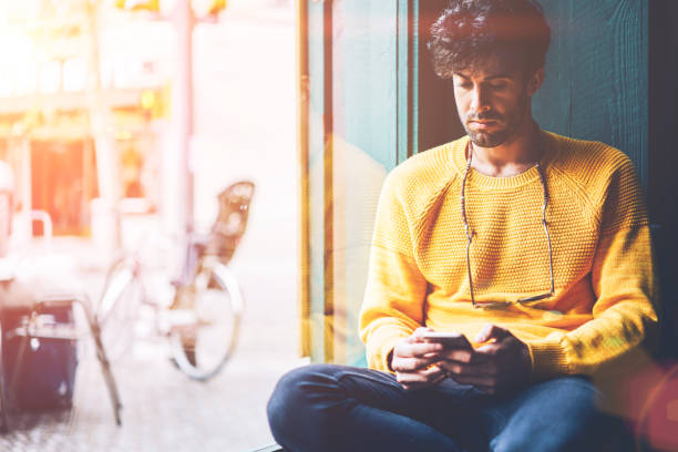 istock Bearded handsome young man w/ith eyeglasses dressed in yellow sweater reading incoming notification on smartphone device connected to 4G internet resting in stylish coworking space 1168817238