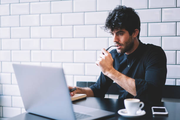 istock Concentrated male graphic designer watching carefully online lesson on laptop computer connected to 4G internet.Pensive entrepreneur checking accounting database on netbook working in coffee shop 1168817263