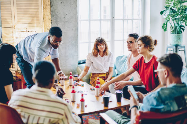istock Multicultural young people dressed in casual wear spending recreation time together playing poker game at table in modern apartment.Diverse hipster guys enjoying entertainment on weekend in flat 1168825315