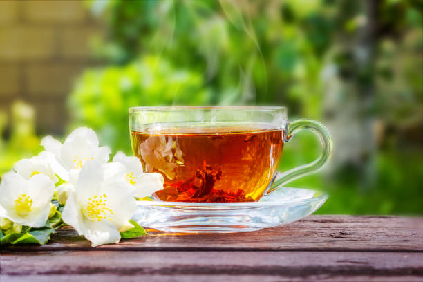 istock Glass cup with tea and jasmine twig on wooden table, on blurred background 1168826458
