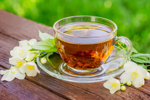 istock Glass cup with hat tea and jasmine twig on wooden table, on blurred background 1168826466