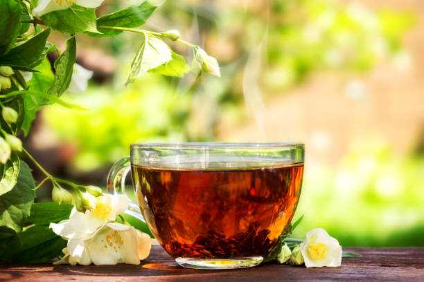 istock Glass cup with tea and jasmine twig on wooden table, on blurred background 1168826483