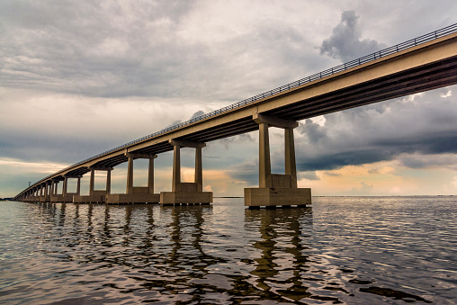 A roadway bridge crossing Lake Pontchartrain just outside of New Orleans, Louisiana near sunset after a storm cleared.