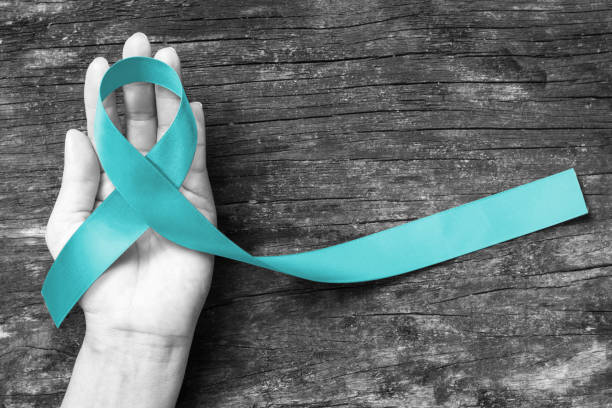 Teal ribbon awareness on woman's hand for Ovarian Cancer, Polycystic Ovary Syndrome (PCOS) disease, Post Traumatic Stress Disorder (PTSD), Tourette's Syndrome, Obsessive Compulsive Disorder (OCD) Teal ribbon awareness on woman's hand for Ovarian Cancer, Polycystic Ovary Syndrome (PCOS) disease, Post Traumatic Stress Disorder (PTSD), Tourette's Syndrome, Obsessive Compulsive Disorder (OCD) polycystic ovary syndrome photos stock pictures, royalty-free photos & images