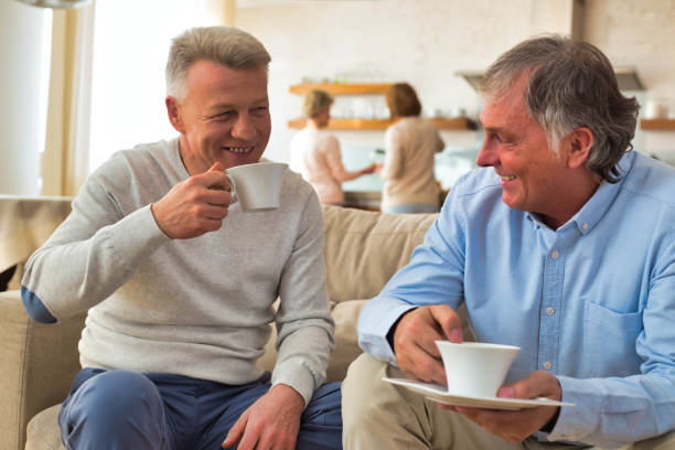 istock Smiling mature men holding coffee while sitting on sofa at home 1168839894