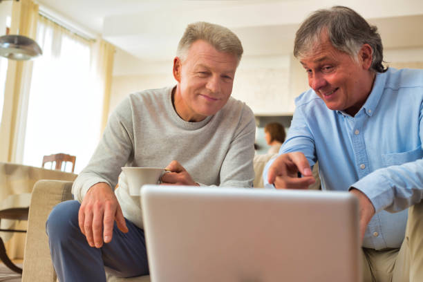 istock Smiling mature men using laptop while sitting at home 1168839999