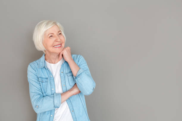 istock Senior woman in jeans jacket studio isolated on grey wall looking aside joyful 1168840685
