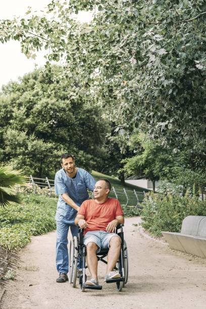 istock man in wheelchair walking with his caretaker 1168842101