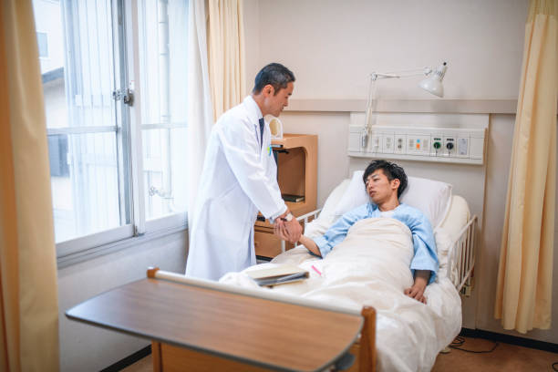 hombre japonés doctor tomando pulso de paciente joven masculino - 3629 fotografías e imágenes de stock