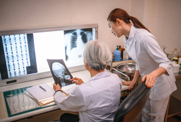 Senior Japanese Doctor and Nurse Studying Illuminated X-Rays