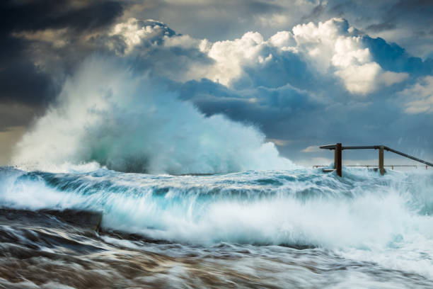 Big waves are splashing at the pier at a stormy day.