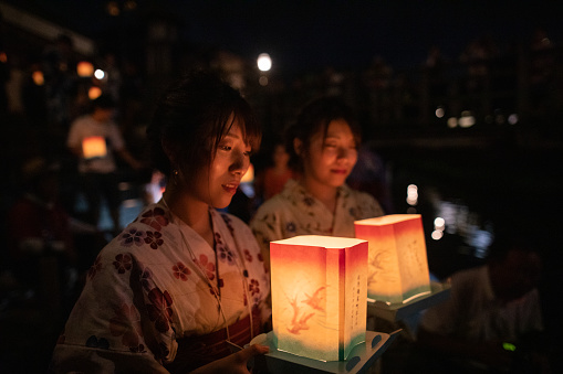 Young adulte sisters holding lantern for floating at summer night event