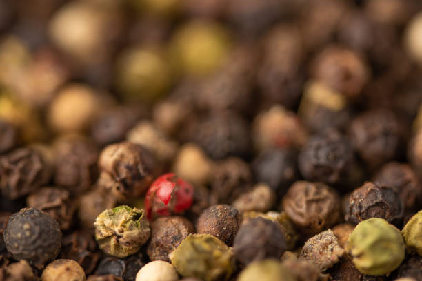 istock Mixed pepper background. black peppercorns and one red pea, closeup. 1168844125