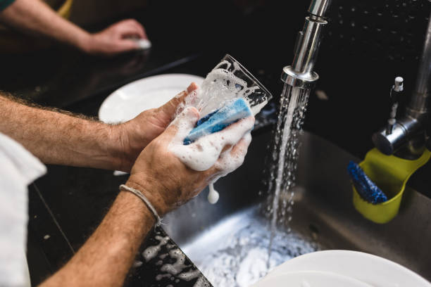 istock A man's hand soaping glasses in the sink 1168847809