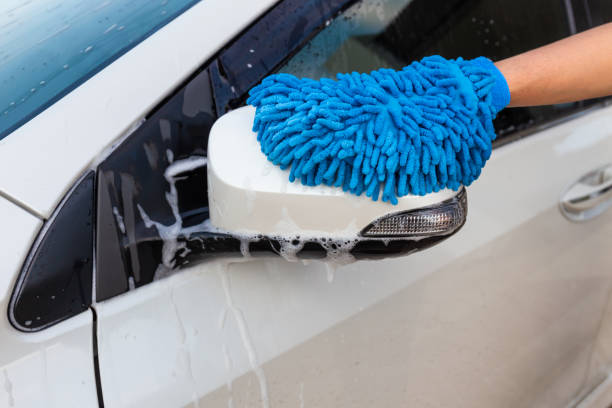 istock Woman hand with blue microfiber fabric washing side mirror modern car or cleaning automobile. Car wash concept 1168852247