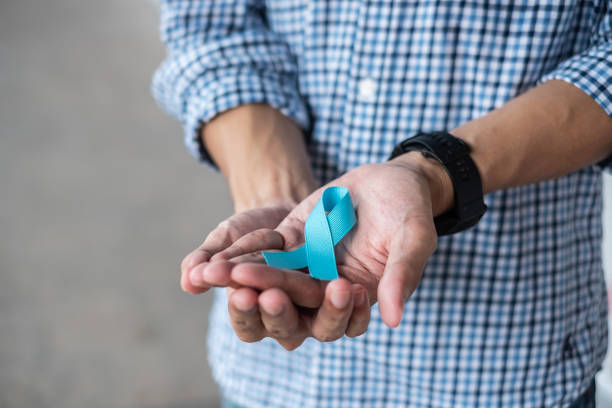 mois de sensibilisation au cancer de la prostate de novembre, homme en chemise bleue avec la main retenant le ruban bleu pour soutenir des personnes vivant et maladie. soins de santé, hommes internationaux, père et concept de la journée mondiale du canc - november photos et images de collection