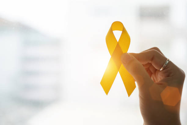 prevenzione del suicidio e consapevolezza del cancro infantile, nastro giallo su sfondo in legno per sostenere le persone che vivono e malattie. bambini salute e mondo concetto di giornata del cancro - riband foto e immagini stock