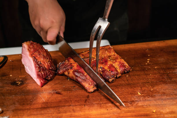 istock Man hand cutting baked ham and grilled ribs 1168865431