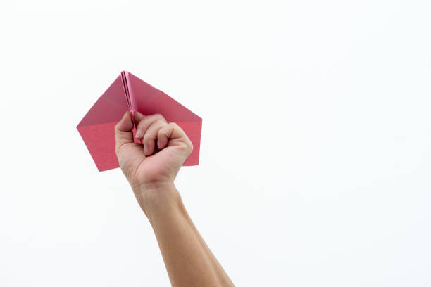 istock Man Hand holding paper airplane against white background 1168876480