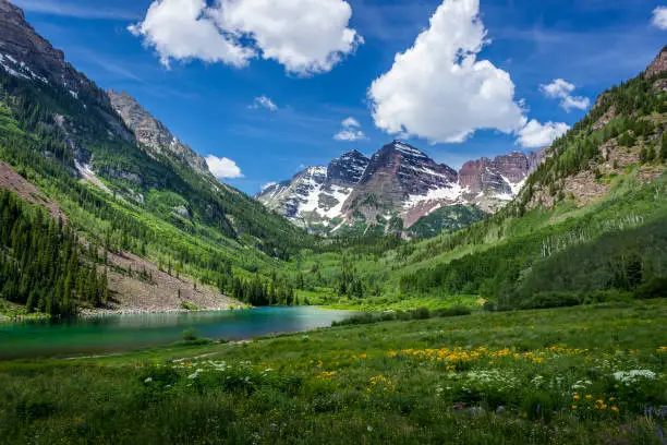 Majestic Maroon Bells peaks and Maroon Lake on a sunny day and blue sky in summer near Aspen, Colorado