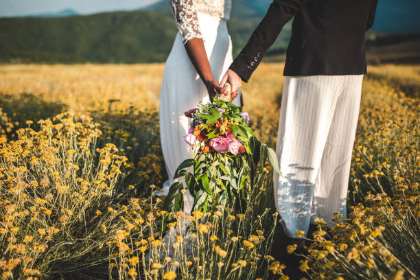 Ready to celebrate their true love Unrecognizable women holding hands and wedding bouquet on agriculture field on sunny day eloping stock pictures, royalty-free photos & images