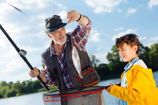 ハンサムな若い興奮した少年はおじいちゃんと釣り - great grandchild ストックフォトと画像