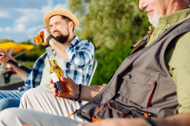 istock Pensioner spending time with son while drinking beer and fishing 1168883725