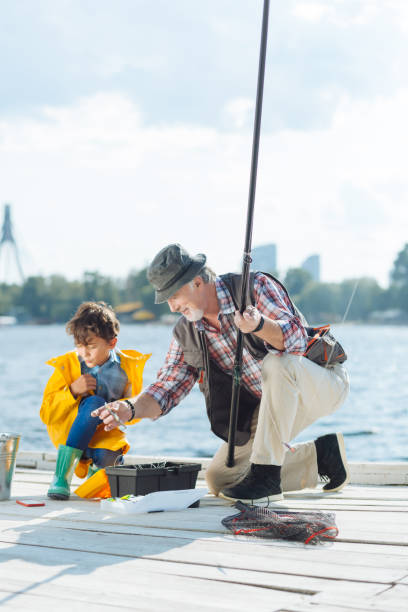 孫と釣りの準備をしている帽子をかぶった祖父 - great grandchild ストックフォトと画像