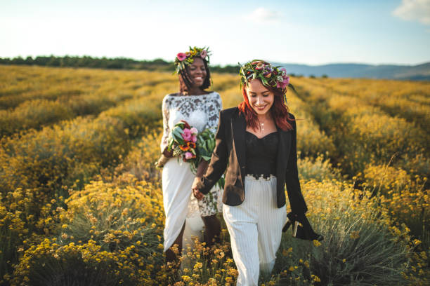 istock Two lesbian brides walking through the yellow flower meadow 1168884475