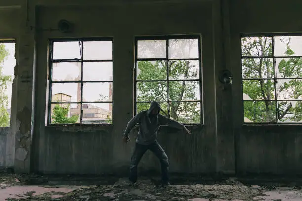 Silhouette of male caucasian hip hop dancer, freestyling outdoors in an old abandoned building