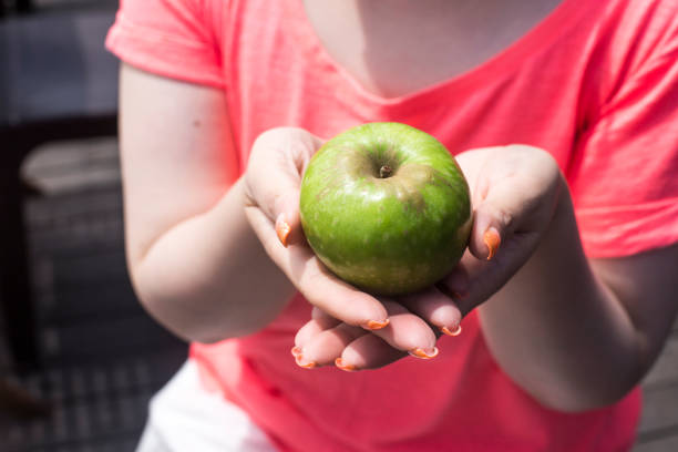 зеленое яблоко в женских руках - granny smith apple стоковые фото и изображения