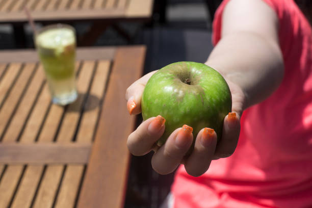 зеленое яблоко в женских руках - granny smith apple стоковые фото и изображения