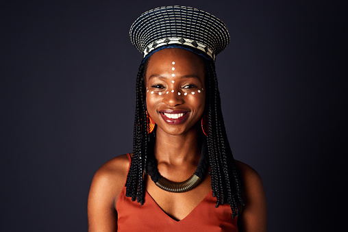 Studio shot of an attractive young woman dressed in traditional african attire posing against a black background