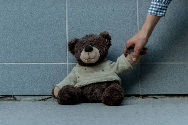 istock human hand grab the dirty teddy bear from the ground outdoors, lost concept 1168890419