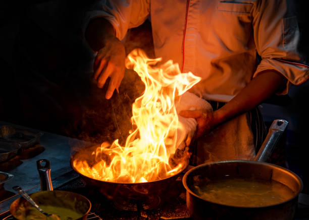 istock Chef cooking with flame in a frying pan on a kitchen stove 1168890824