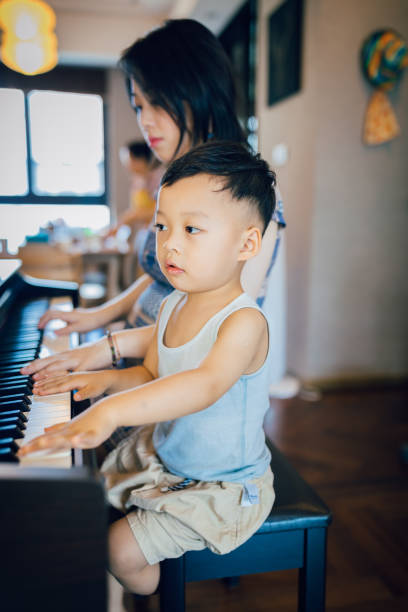 istock Chinese mother teaching her son how to play piano. 1168891667