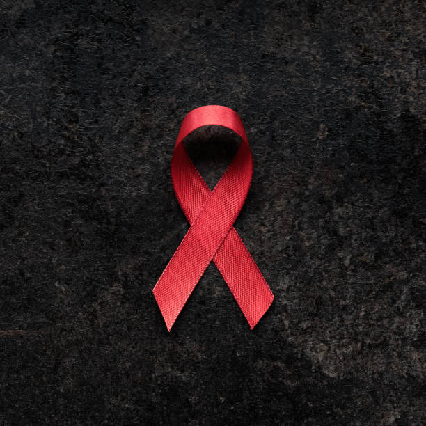 cinta roja de concienciación sobre el sida sobre fondo oscuro - aids awareness ribbon fotos fotografías e imágenes de stock