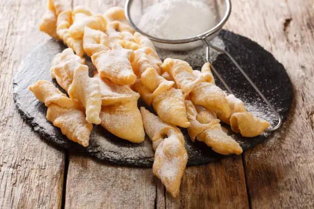 Polish dessert faworki with powdered sugar close-up on the table. horizontal